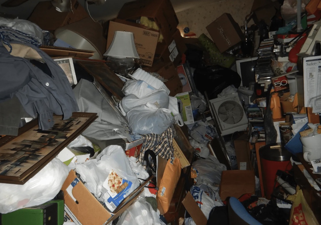 Crowded Farmington Hills room with household clutter before cleanout